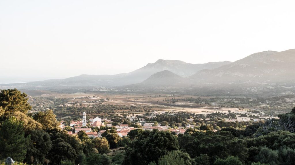 Vue panoramique au crépuscule sur le village de Calenzana, avec ses maisons traditionnelles et les montagnes, symbolisant tranquillité et connexion avec la nature.