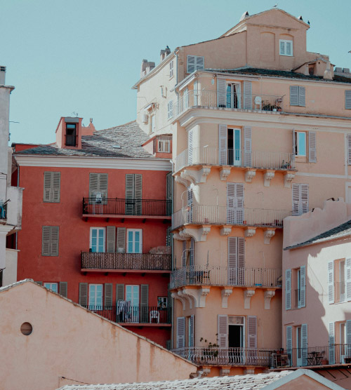 L'image illustre le charme pittoresque de Bastia avec ses bâtiments colorés et ses balcons, créant une atmosphère festive et accueillante, un véritable tableau vivant aux multiples couleurs, parfait pour les amateurs de photographie.