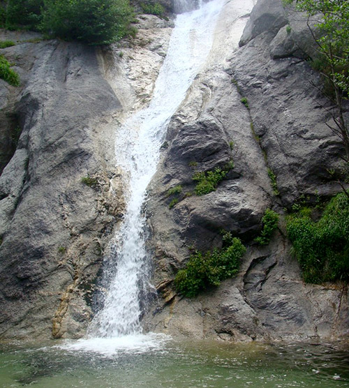 Image d'une chute d'eau spectaculaire entourée de rochers majestueux et de verdure abondante, créant une harmonie entre la force naturelle et la sérénité.