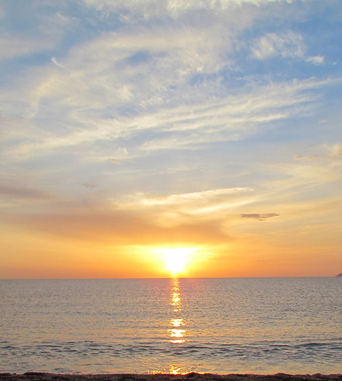 Coucher de soleil flamboyant sur l'horizon maritime avec reflets dorés dans l'eau, créant une ambiance magique et apaisante.