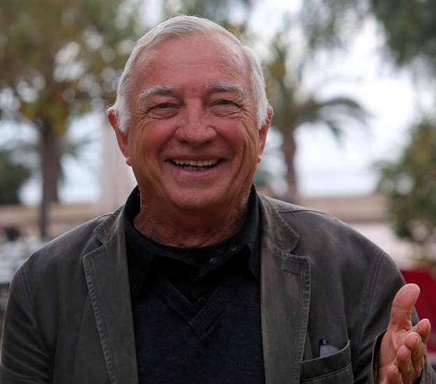 Homme souriant en plein air sous des palmiers, capturant un moment de convivialité et de bonheur.