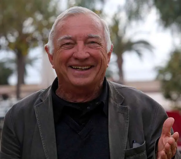 Homme souriant en plein air sous des palmiers, capturant un moment de convivialité et de bonheur.