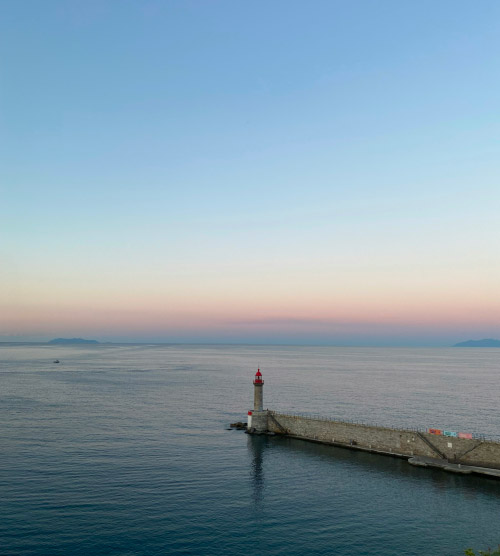 Cette image capture un phare majestueux en Corse au coucher de soleil, créant un paysage serein et romantique au bord de la mer Méditerranée.