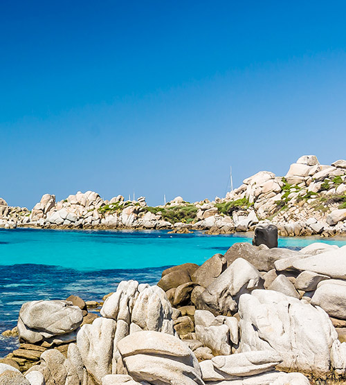 Image de la plage de Balai en Sardaigne montrant ses eaux cristallines et ses récifs, éclairée par le soleil.