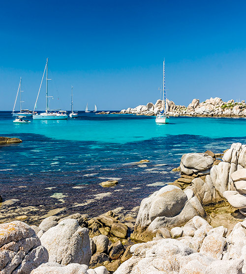 Côte corse baignées de lumière, voiliers sur mer turquoise, calme et beauté naturelle.