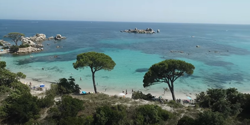 Photo de plage en Corse avec ses eaux cristallines, reflet azur et sable doré, idéale pour des vacances estivales inoubliables.