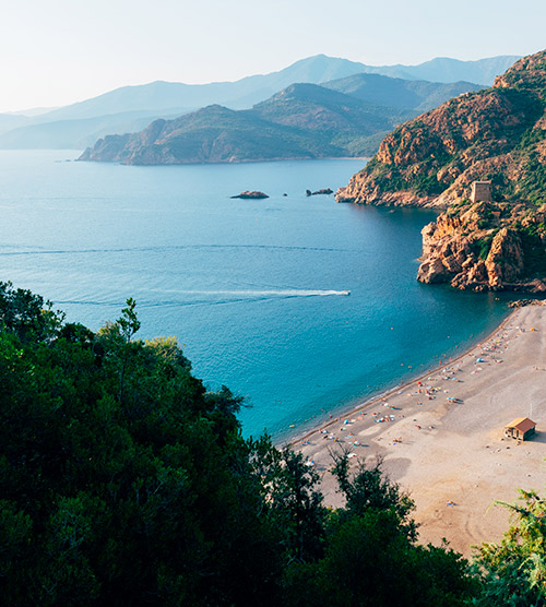 Plage idyllique avec montagnes, mer turquoise et ciel limpide, parfaite pour des vacances paisibles et se ressourcer en pleine nature.