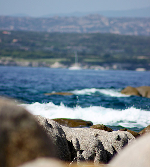 Cette image plonge dans l'atmosphère sereine d'une plage corse avec des rochers imposants et des vagues caressantes, idéale pour les amoureux de la nature en quête de tranquillité.