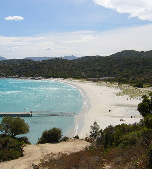 Plage idyllique avec sable blanc, eaux turquoise et montagnes verdoyantes en arrière-plan, offrant une atmosphère apaisante et propice à l'évasion.