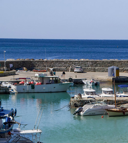 Cette image capture un port paisible où des bateaux flottent sous un ciel bleu, évoquant détente et évasion vers des rivages ensoleillés.