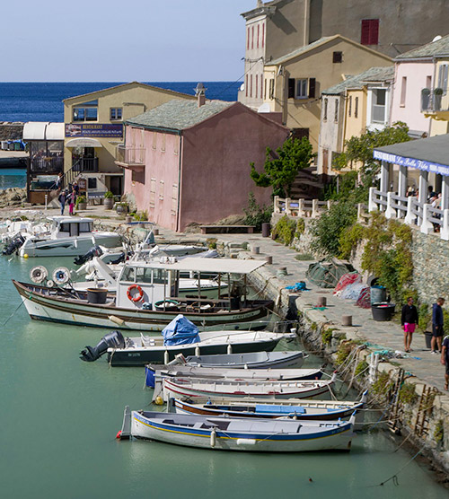 Port méditerranéen vibrant avec bateaux, lumière du jour et façades colorées, reflétant une escapade estivale animée.
