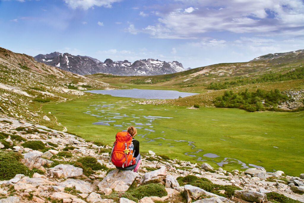Scène de randonnée avec lac paisible et montagnes majestueuses, invitant à l'évasion et à la contemplation en pleine nature.
