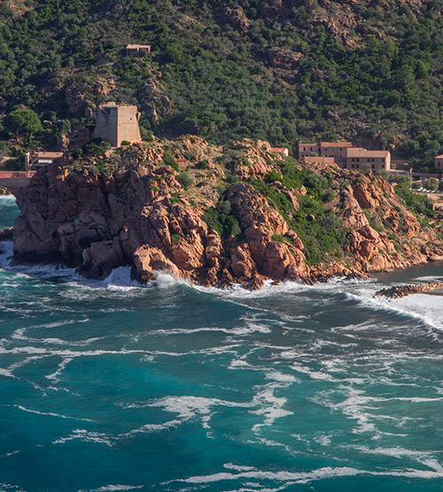 Vue imprenable sur un rocher majestueux surplombant des vagues, ornée d'une tour historique, un site alliant nature et histoire.