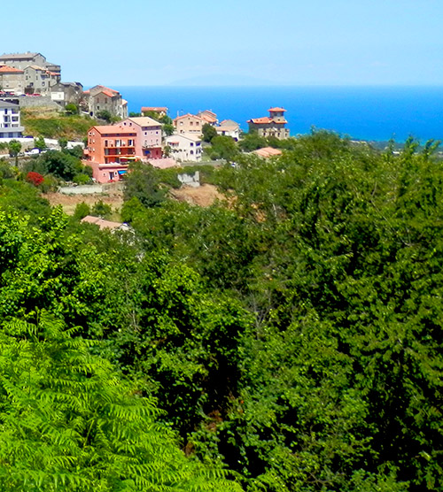Image d'un village méditerranéen pittoresque perché sur une colline avec vue sur la mer, entouré de végétation luxuriante, ciel clair et ambiance chaleureuse.