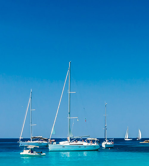 Des voiliers naviguent paisiblement sur une mer turquoise, créant une harmonie avec le bleu profond du ciel, capturant l'essence de la détente estivale.