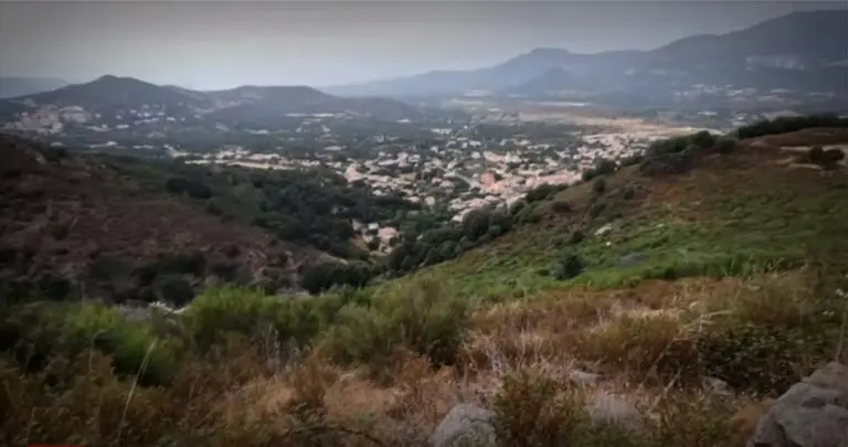Vue panoramique d'un village niché au cœur des montagnes verdoyantes, reflétant beauté et sérénité.