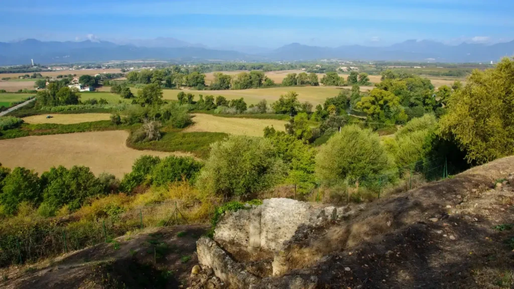 vue-panoramique-aleria-plaine-orientale Vue panoramique depuis les hauteurs d'Aleria sur les murets en ruine du site archéologique, la plaine orientale verdoyante et les montagnes lointaines.