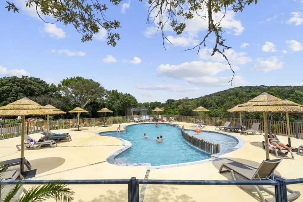 Piscina da campeggio all'aperto circondata da verdi colline, ideale per una rilassante vacanza estiva in famiglia.