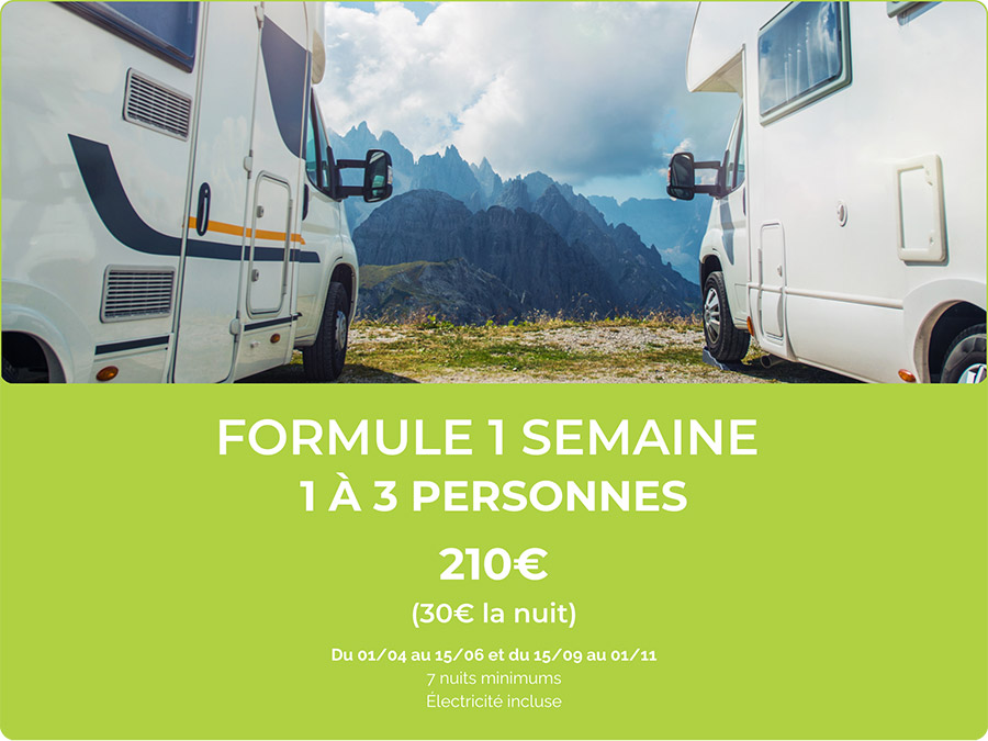 Une majestueuse vallée montagneuse avec camping-cars entourés par des montagnes et un ciel nuageux, parfaite pour une aventure en plein air.