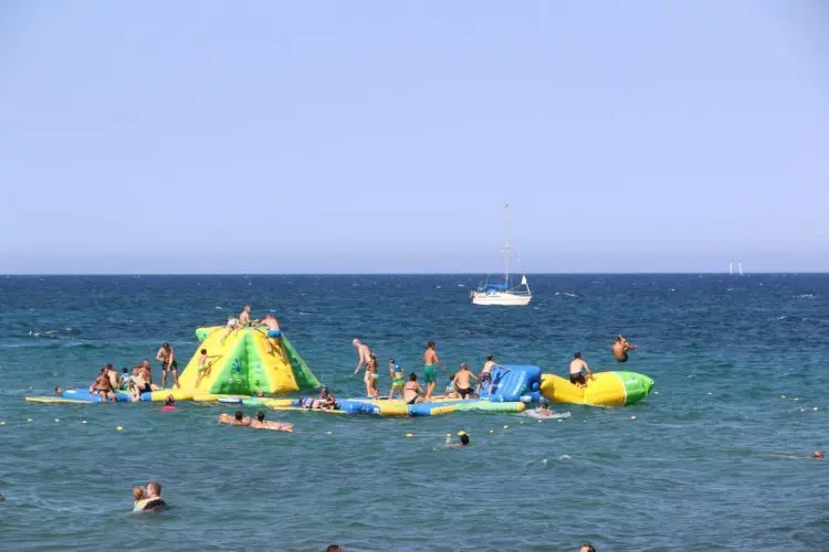 Jeux d'été sur la plage de San Nicolao avec activités aquatiques et ambiance festive parmi les amis et familles, sous le soleil méditerranéen.