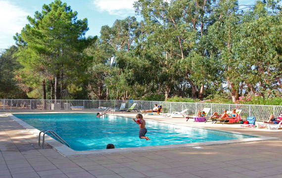 Enfants s'amusant autour d'une piscine en plein air, entourée de verdure, évoquant des journées estivales idéales.