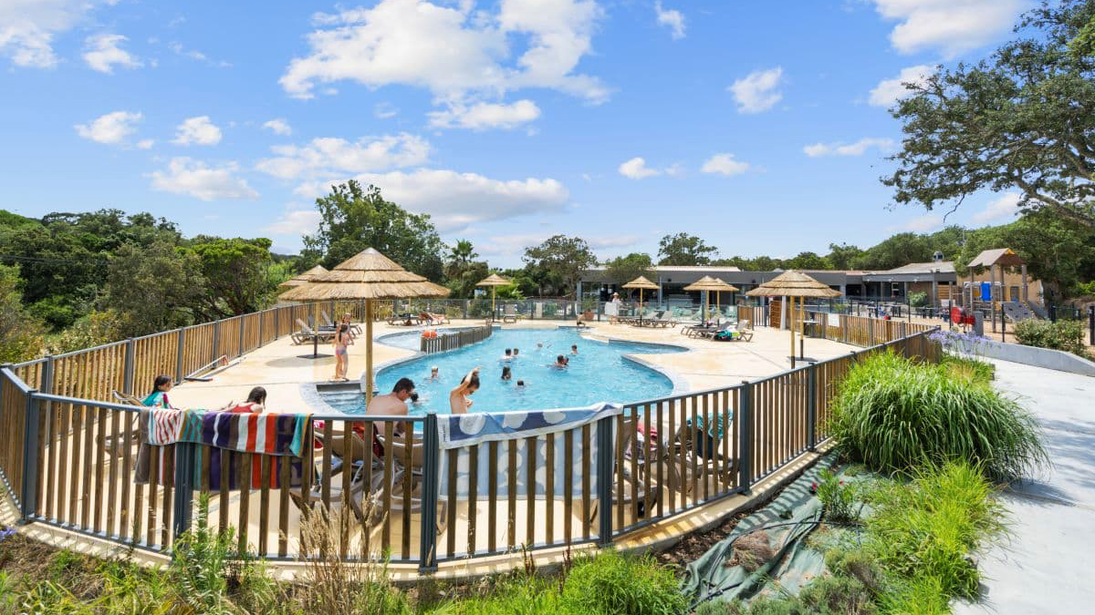 Une journée d'été en famille au bord de la piscine, sous un ciel ensoleillé, avec des rires d'enfants, des parasols colorés et une ambiance de détente mémorable.