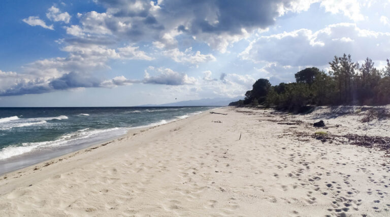 Image d'une plage tranquille avec sable doré et ciel nuageux, parfaite pour la relaxation et la contemplation naturelle.