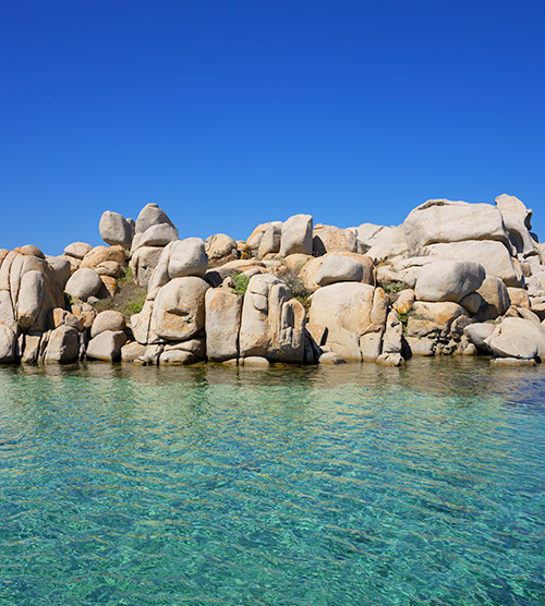 Paysage côtier serein avec rochers et mer bleu éclatant sous ciel azur, parfaite illustration de la beauté naturelle et apaisante.
