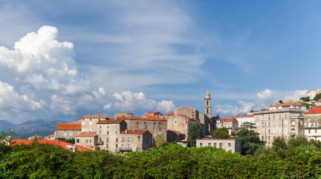 Cette image illustre la sérénité d'un charmant village historique en été, avec des maisons en pierre sous un ciel azur, idéal pour les amateurs de patrimoine et de tranquillité.
